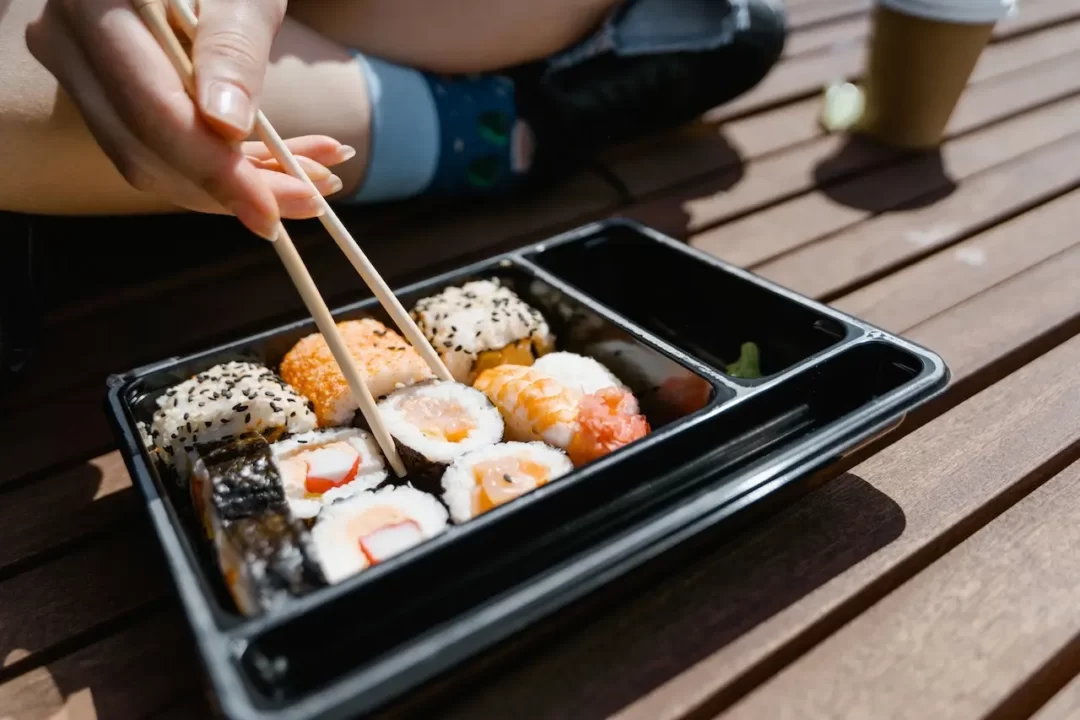 a person holding sushi with chopsticks